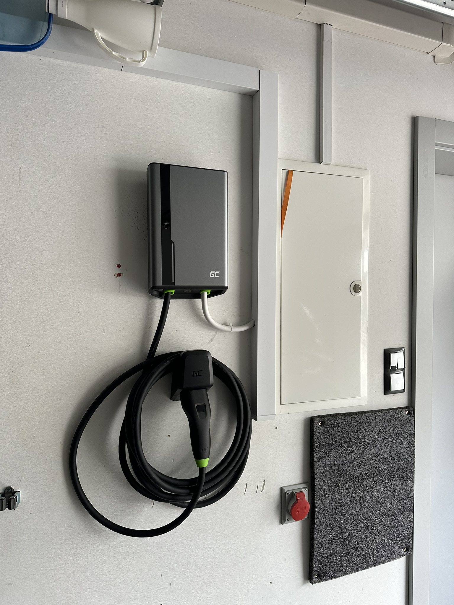 Wallbox GC na ścianie garażu, z przewodem i uchwytem wtyku.